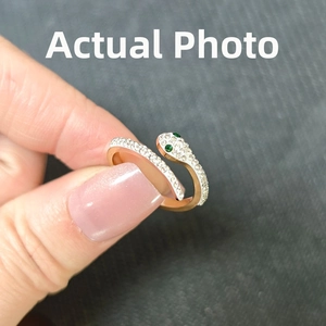Détail macro de la bague serpent en or rose sertie de zircons et yeux en pierre verte