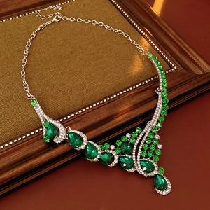 Detail of vintage necklace with green teardrop crystal and rhinestones on a rustic base