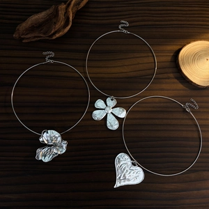 Gros plan artistique de pendentifs cœur et pétales en métal sur fond de bois sombre