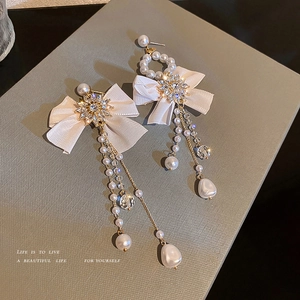 Elegant bow fringe tassel earrings with creamy pearls and crystals on a gift box