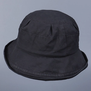 Detailed top view of a plain black cotton bucket hat with a wide brim on a gray background
