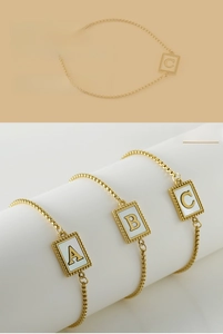 Detailed view of gold beaded chain bracelets with shell initial pendants A, B, and C