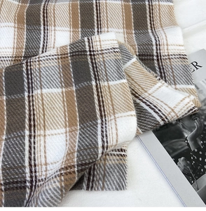 Close-up of winter plaid scarf texture in coffee and khaki with soft knit pattern