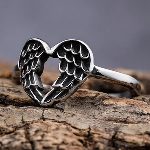 Retro stainless steel wing heart ring displayed on a natural tree bark background