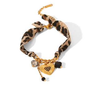 Detailed view of leopard print fabric bracelet with gold chain and black crystal heart charm