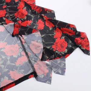 Dettaglio della stampa a rose rosse su tulle nero con bordo a balze e cucitura overlock