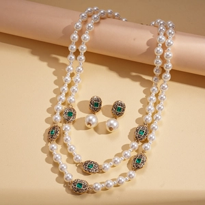 Nahaufnahme eines Vintage Perlen-Schmucksets mit grünen Edelsteinen und goldenen Details