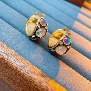 Detail of vintage palace style gold earrings with black base and colorful gemstones
