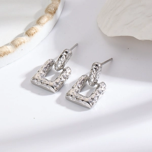 Detail of silver square stud earrings with unique hammered texture on white background