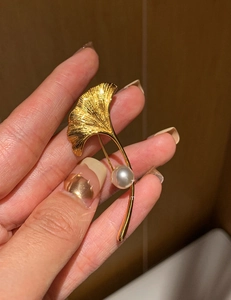 Dettaglio della spilla a foglia di ginkgo placcata oro 18K con texture spazzolata e perla