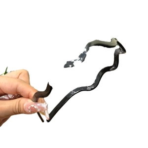 Minimalist black wavy resin headband accessory shown on a clean white background