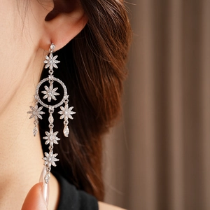 Detail of silver flower tassel earrings with zircons shown on a model for a luxury look