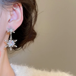 Nahaufnahme eleganter Schneeflocken-Ohrringe mit Zirkonia-Steinen an einem Modell