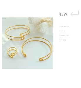 Close-up of a gold-plated jewelry set featuring two open bracelets and a matching ring