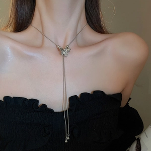 Detail of silver butterfly tassel necklace with hollow charm worn on neck