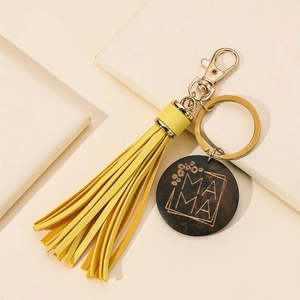 Detail of mama engraved wooden pendant with yellow tassel and golden metal keychain hook