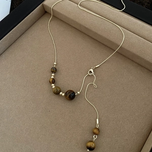 Detailed macro view of golden chain necklace with multiple polished tiger eye stone beads