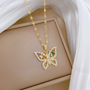 Detailed shot of gold butterfly pendant with colorful zircons on white silk background