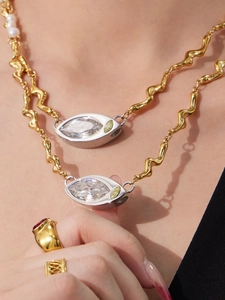 Detail of gold wavy chain necklace with large rhinestone pendant and freshwater pearl accents