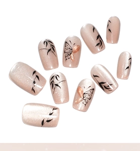 Détail macro d'ongles nude œil-de-chat avec motifs feuilles et décor papillon 3D