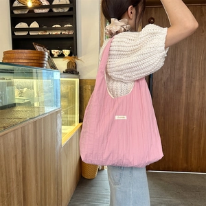 Pink pleated tote bag shown in a cozy cafe setting with detailed fabric texture
