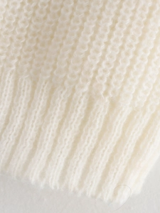 Gros plan du tissu en maille crème montrant le tissage fin et les bords côtelés