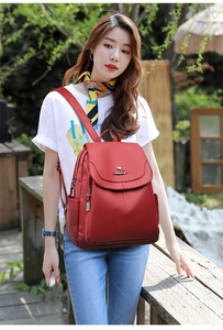 Detail of red leather-textured backpack with gold kangaroo logo and side pocket view