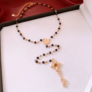 Collier vintage à pendentif clé avec gemme marron et perles noires sur satin blanc