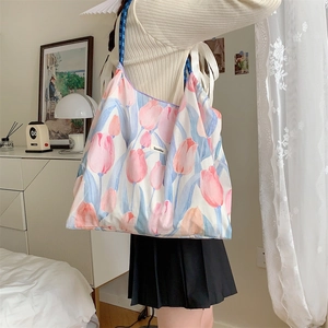 Detail of floral tulip print tote bag with blue braided rope handles in a modern interior
