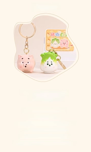 Macro shot of cute cartoon pig and cabbage charms on golden metal keyrings