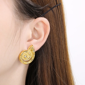 Detailaufnahme der 18K vergoldeten Spiralohrringe mit kleinen Strasssteinen am Modelohr