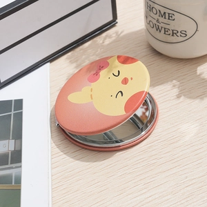 Portable round folding makeup mirror with cartoon puppy design on light wood surface