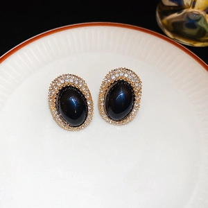 Macro view of vintage oval stud earrings with black gemstone and crystal halo