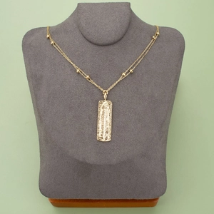 Golden feather pendant necklace with beaded chain on dark grey mannequin bust