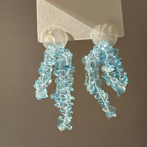 Gros plan de glands en pierre bleu clair et base ronde blanc laiteux sur boucles d'oreilles