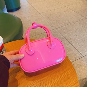 Close-up of a mini bright pink jelly PVC handbag featuring dual handles and glossy finish