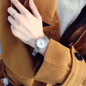 Silver ladies mesh watch with white dial and Quartz movement shown on a wrist with a ring