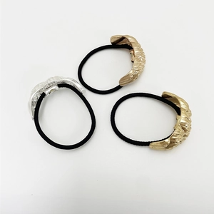 Detailed shot of elastic hair ties featuring textured gold and silver metal accents