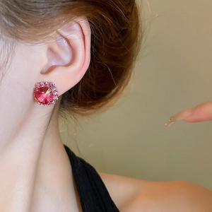 Close-up of pink crystal stud earrings worn by a model with shimmering accents