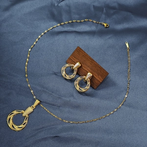 Macro detail of golden geometric spiral necklace and earring set on dark fabric