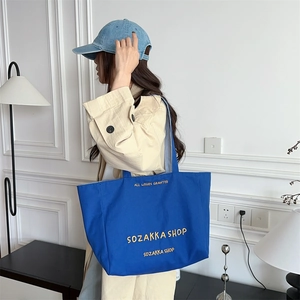 Detail der royalblauen Canvas-Tasche mit gelber Stickerei und robustem Schultergurt