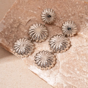 Macro shot of silver tiered ribbed dome earrings on a textured stone display