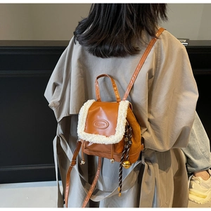Detail of brown PU leather backpack with white faux fur trim and fashion metal tag