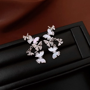Détail macro de boucles d'oreilles pampilles en argent avec papillons et zircons