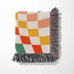 Close-up of bohemian knit blanket with colorful warped checkerboard pattern and fringe