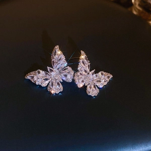 Macro shot of sparkling silver butterfly stud earrings with zircon stones on dark surface