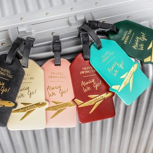 Faux leather luggage tags in various colors hanging on a silver striped metal suitcase