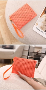 Detail of orange woven mesh clutch bag with golden zipper and sturdy wrist strap