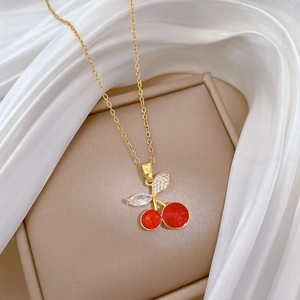 Detailed close-up of a gold cherry pendant necklace with red crystals and zircons