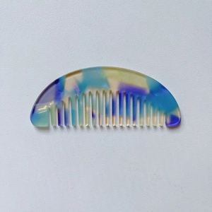 Detail shot of a semi-circular marble pattern acetate hair comb in vibrant mixed colors